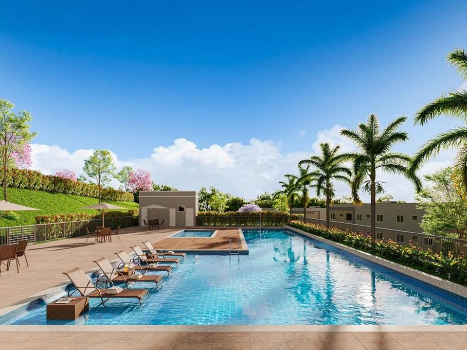 Perspectiva ilustrativa da piscina do Vila Serrana, com espreguiçadeiras, mesas com guarda-sol, palmeiras e blocos de apartamentos ao fundo